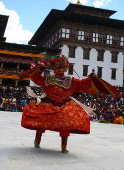 Tänzer beim Thimphu Tempelfest mit dem Thimphu Dzong im Hintergrund