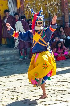 Tänzer beim Thimphu Tempelfest mit dem Thimphu Dzong im Hintergrund